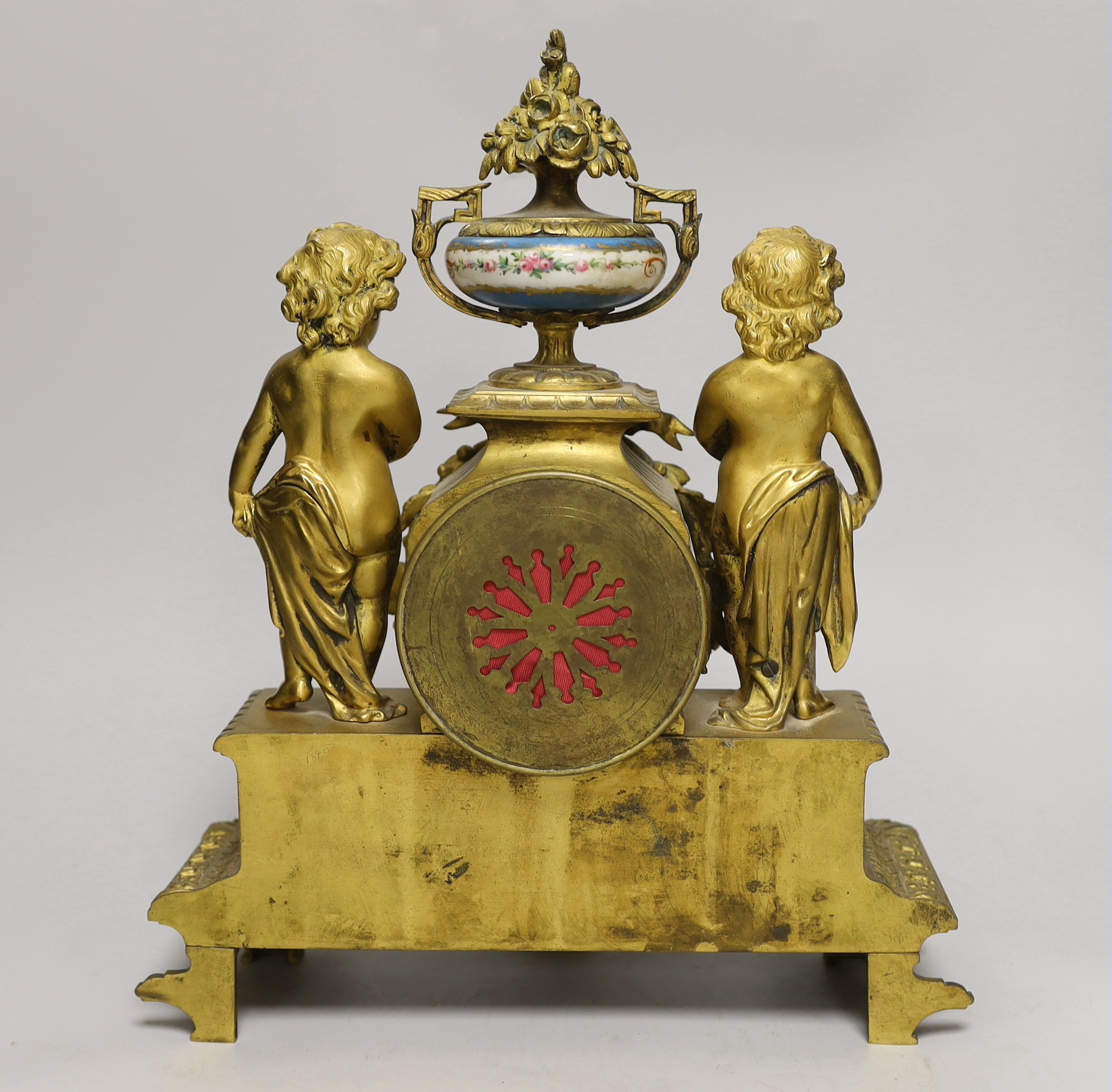 A French decorative ormolu putti mantel clock with porcelain clock face, side panels and urn